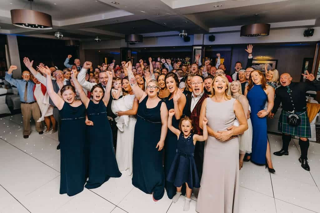 Guests cheering at the camera at a wedding at Lochside Hotel