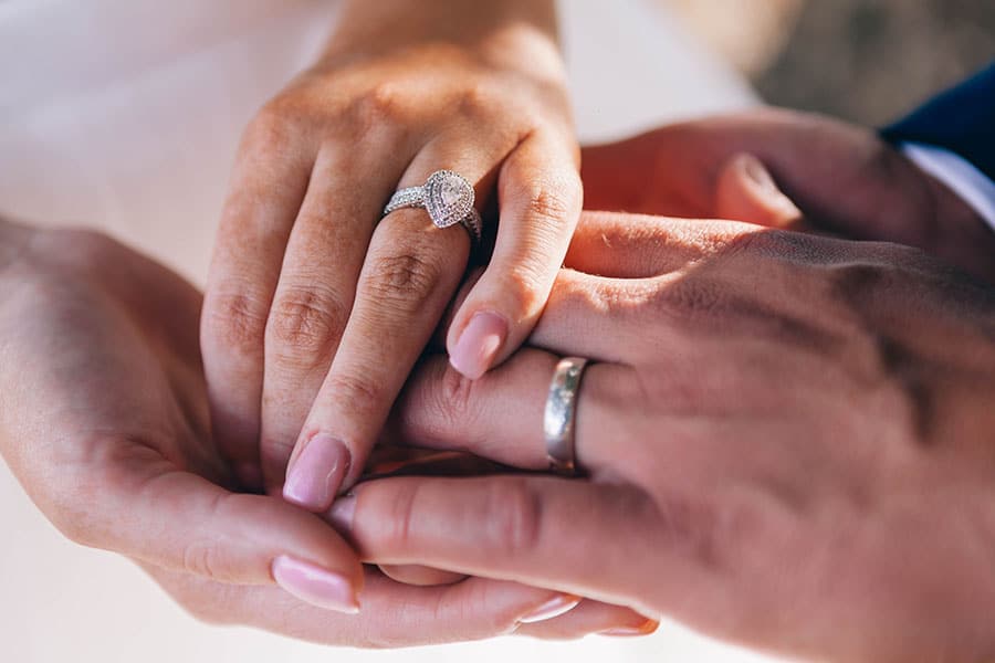 A couple holding hands with their engagement rings on display for the photograph