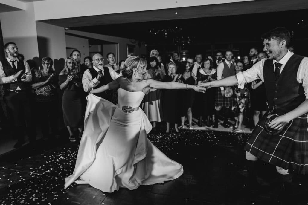 Bride and groom dancing their first dance with guests around them