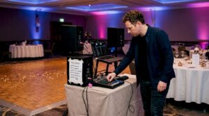 Wedding DJ adjusting mixer beside empty dancefloor